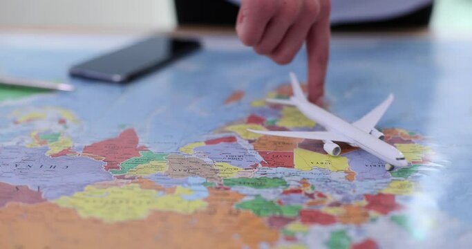 Woman travel agent plays with model airliner over flat map