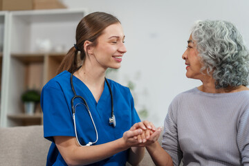 Caucasian female doctor offers encouragement to Asian mature elderly patient woman while holding...
