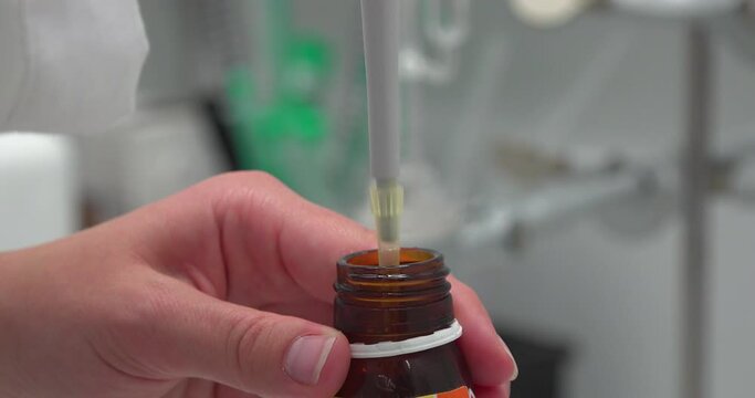 Pipette nimmt Fl&uuml;ssigkeit aus brauner Glasflasche auf