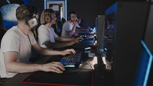 Gamers team plays a video game on PC at computer club, cyber sport tournament. E-sport championship. 5 players in in headset. Multiplayer online battle competition, tactical first-person shooter