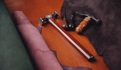 Leather rolls of natural color and tools for handmade craft in workshop. Banner tailor industry...