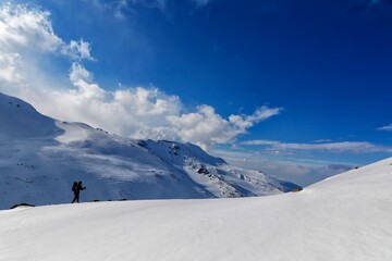 Fototapeta na wymiar Person ascending a snowy mountain slope