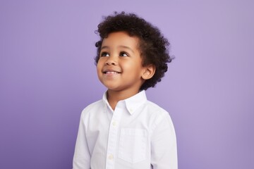 happy african american little boy in white shirt over purple background