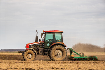 Obraz premium A modern tractor tilling farmland, preparing the soil for planting crops