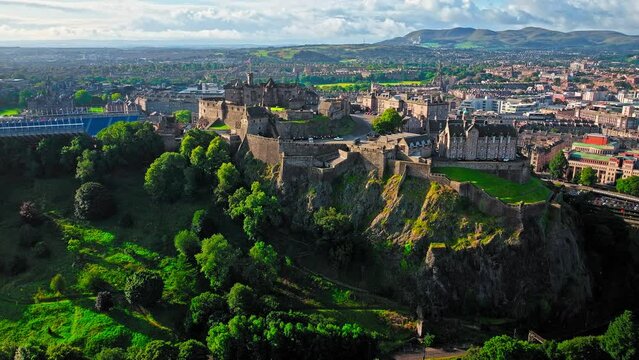Aerial view of Edinburgh Castle with green gardens in Scotland. Historic castle and barracks housing the Crown Jewels and National War Museum of Scotland stands on Castle Rock.
