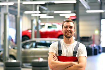 portrait of a smiling car mechanic in car workshop in woking clothes - occupation workmen - 758701340