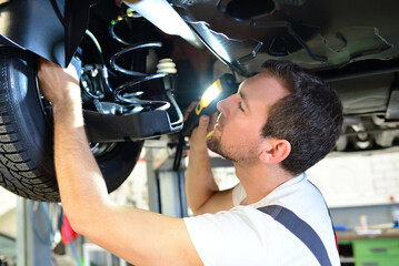 professional car mechanic works in a workshop and repairs vehicles - check the technology, brakes...