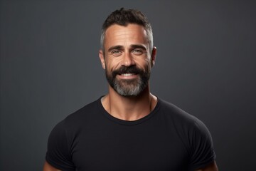 Portrait of handsome mature man in black t-shirt over grey background.