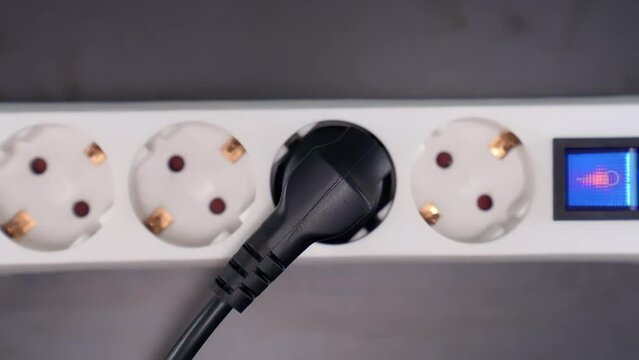 Electrical extension cord with electrical plug. Extension cord on a gray background. The black and white plug are plugged into the socket in the extension cord.