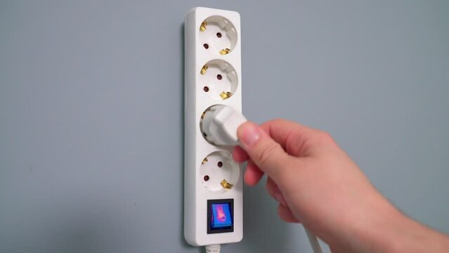 Electrical extension cord with electrical plug. Extension cord on a gray background. The black and white plug are plugged into the socket in the extension cord.