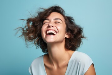 Portrait of a happy young woman with flying hair over blue background - Powered by Adobe