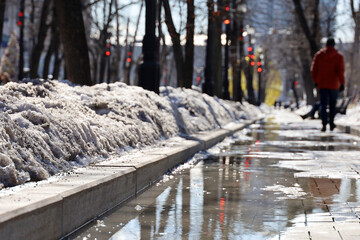 Puddle on city street with melting snow in spring
