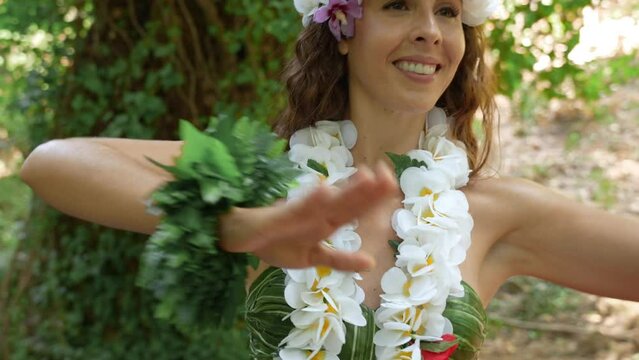 Detail shot of the face of a smiling woman enjoying a tropical forest dancing Hawaiian dances.