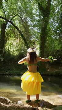 Unrecognizable woman dancing for the sun inside the river a traditional Polynesian hula dance with back shot view.