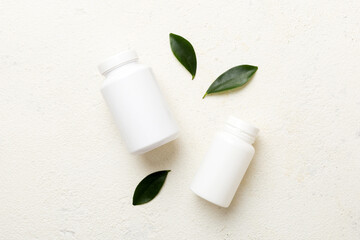 supplement pills with medicine bottle health care and medical top view. Vitamin tablets. Top view mockup bottle for pills and vitamins with green leaves, natural organic bio supplement, copy space