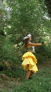 Energetic woman performing traditional Hawaiian dance on the forest vegetation, very happy and joyful.