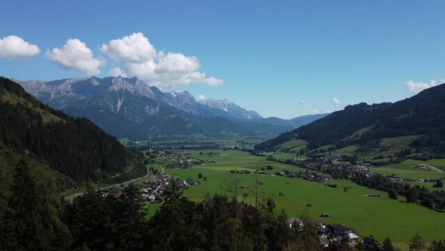 Drone slowly flying along a lush green alley in the mountain ranges of Leogang, Austria, in the sunshine
