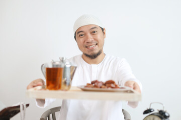 Smiling Muslim Man Serving Dates Fruit and Hot Tea for Breakfasting Iftar on Ramadan Month 