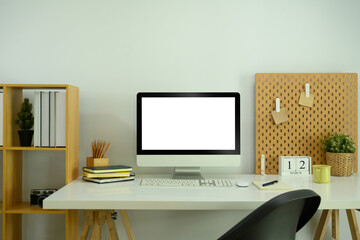 Front view of empty computer monitor and stationery on white table in home office