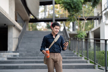 Fototapeta premium Smiling asian businessman walking to work while to hold reusable eco friendly ecological cup in the city