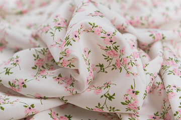 Close-up of texture fabric background with a batist white colour with a floral pattern pink colour. Background, drapery fabric texture with printed little flowers.