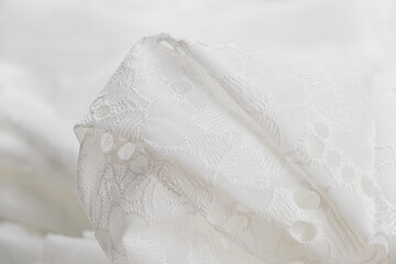 Obraz na płótnie Canvas Close-up of texture of white sangalo cotton sangalo fabric with lace. Background, texture of draped fabric with lace, .elegant embroidery, art of decorating material..