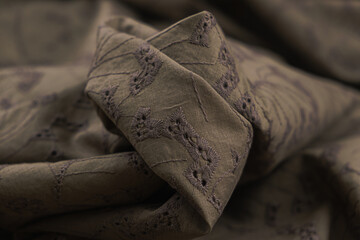 Close-up of texture of brown sangalo cotton fabric with lace in the form of small flowers....