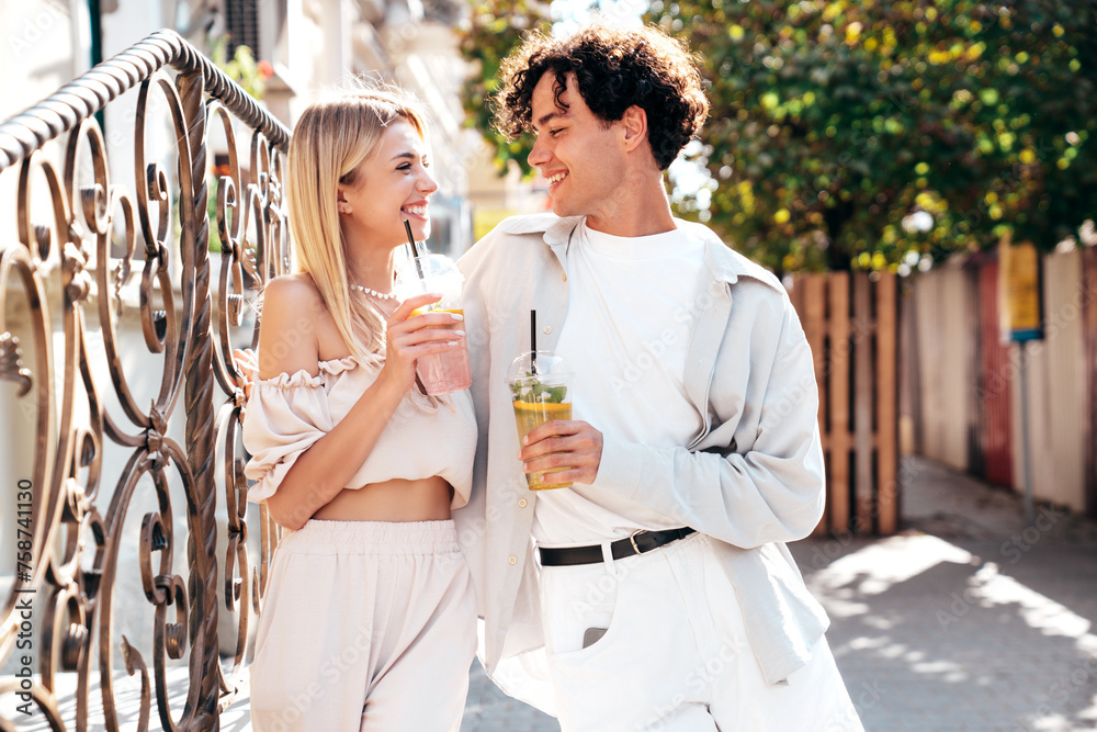 Canvas Prints Young smiling beautiful woman and her handsome boyfriend in casual summer clothes. Happy cheerful family. Female having fun. Couple posing in street. Holding and drinking cocktail drink in plastic cup