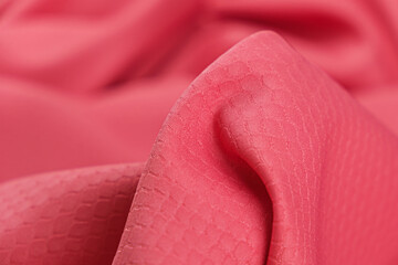 Close-up of pink color dress stretch fabric with snakeskin texture. Background, draped fabric...