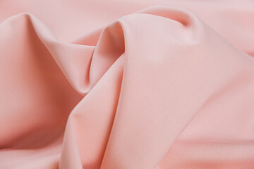 Close-up of texture of cotton fabric in peach-pink color. Background, texture of draped fabric...