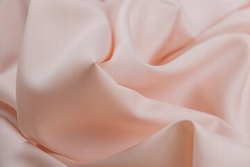 Close-up of texture of cotton fabric in peach-pink color. Background, texture of draped fabric...