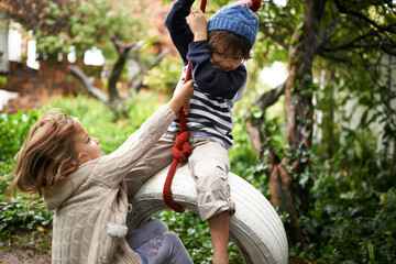 Children, smile and swing in a backyard in fall together with sibling and fun in garden. Youth,...