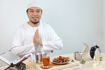 Muslim Man Gesture Welcoming and Greeting For Ramadan with Iftar Food and Ramadan Decoration On The Table