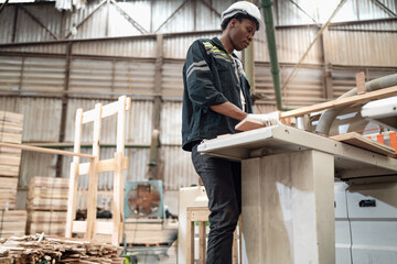 Multiracial worker standing in warehouse examining hardwood material for wood furniture production. Engineer wear safety hardhat uniform working in lumber pallet factory. Supervisor check merchandise