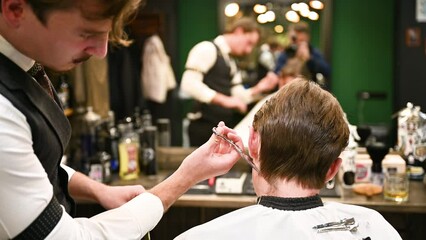 Experienced barber using comb and scissors to cut extra hair in barbershop.