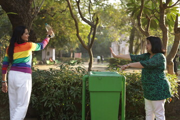 Woman telling young girl, not to throw garbage or plastic trash in park or public place to keep...