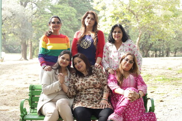 Fototapeta premium Reunion of happy Indian women. green park lush green atmosphere. tranquil and serene environment. elderly old friends together. three women in park having fun in day time. ladies enjoying.