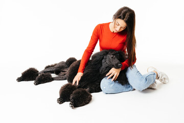 Smiling Young Woman in Red Top Bonding With a Large Black Dog Inside a Studio