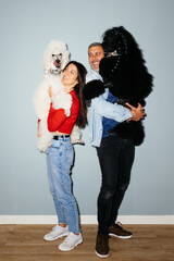Happy Couple Holding Their Large White and Black Poodles Indoors