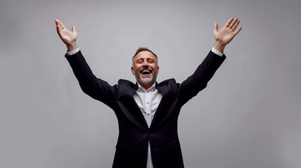 Mature businessman in a business suit with hands raised in happiness on a white background. - 758761172