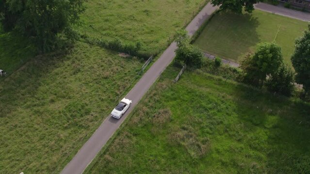 Aerial view of white oldtimer wedding car driving on small road, Netherlands