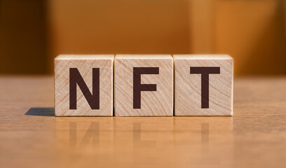 There is wood cube with the word NFT. It is an abbreviation for Non-Fungible Token as eye-catching...