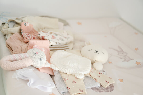 New baby clothes and toys on a bed