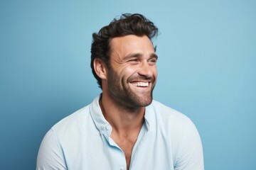 Portrait of happy man laughing and looking at camera over blue background