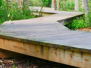 Low view of a wooden boardwalk with no rails zig zag back and forth leading lines on a nature...