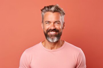 Portrait of handsome mature man with beard and mustache in pink t-shirt. Studio shot.