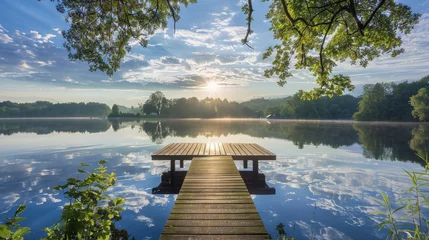 Tuinposter Reflectie A wooden dock extends over a tranquil lake, reflecting the clear blue sky above on a sunny day