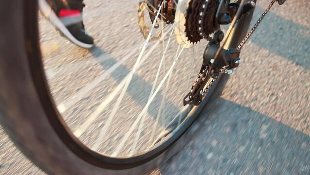 A man rolls a bicycle with a punctured rear wheel along an asphalt road. A broken tube in a wheel tire. Slow motion, close-up