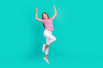 Full size photo of pretty teenager girl jumping raise hands wear trendy print pink outfit isolated...