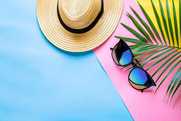 Sunglasses on striped Pastel Background with Tropical Palm Leaves and straw hat. Creative Pop Art...